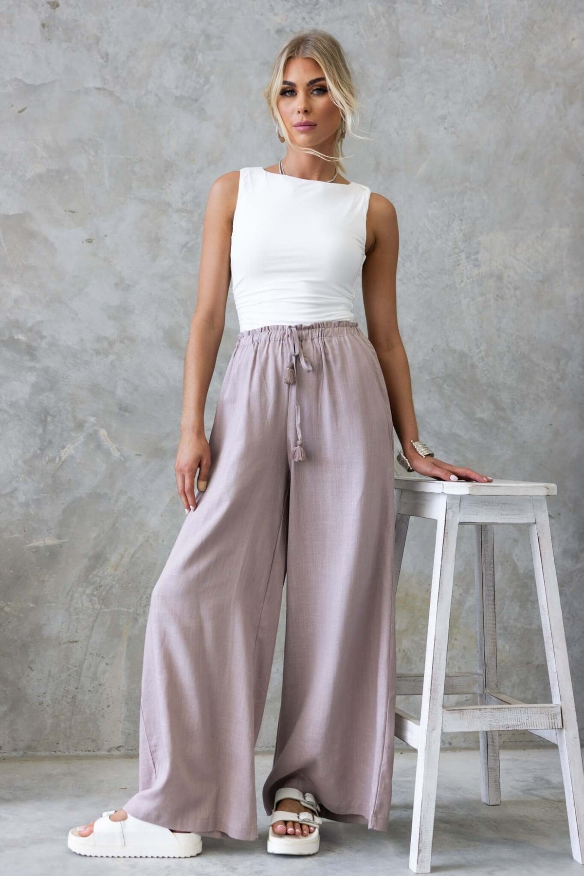Marcia Pants in soft linen with high waist and pockets, styled with a white tank top for a casual look.