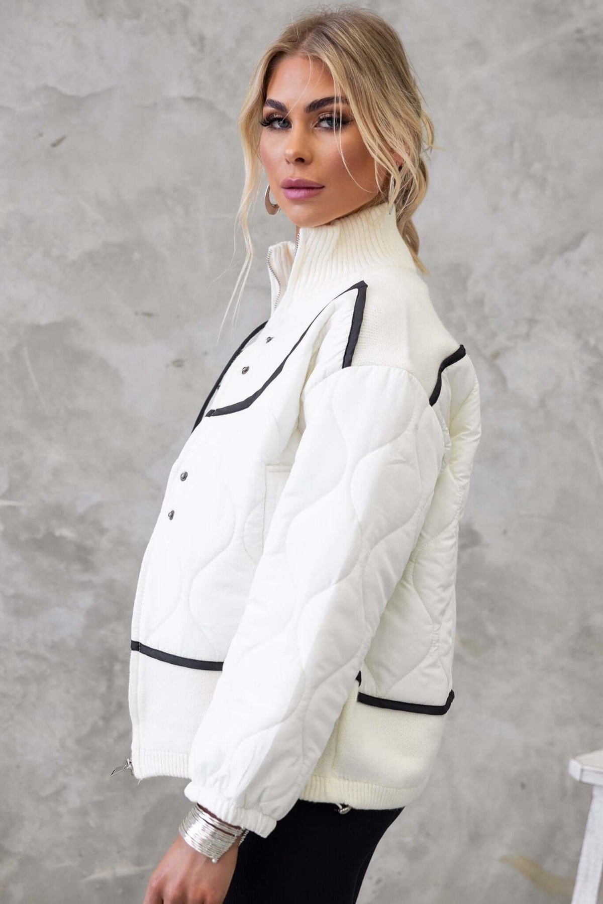 Model wearing the Carota Jacket, featuring a high neckline, zip front, and quilted material in white.