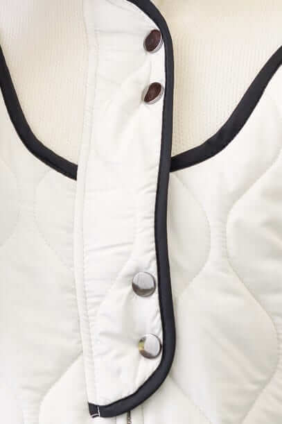 Close-up of Carota Jacket featuring quilted material, high neckline, and snap buttons for stylish functionality.
