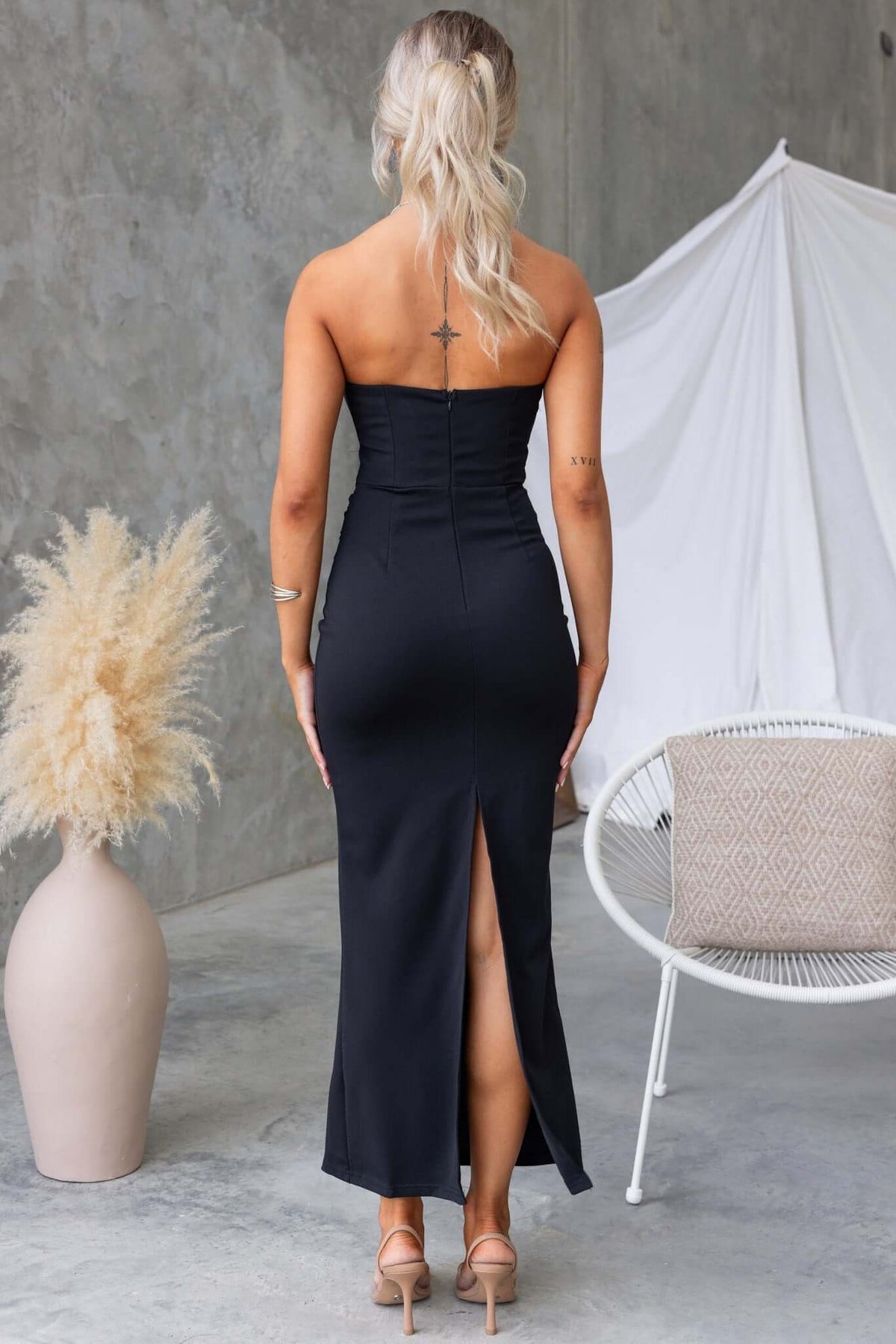 Back view of the strapless black Sassari Maxi Dress with a split, featuring an elegant silhouette and lace detail.