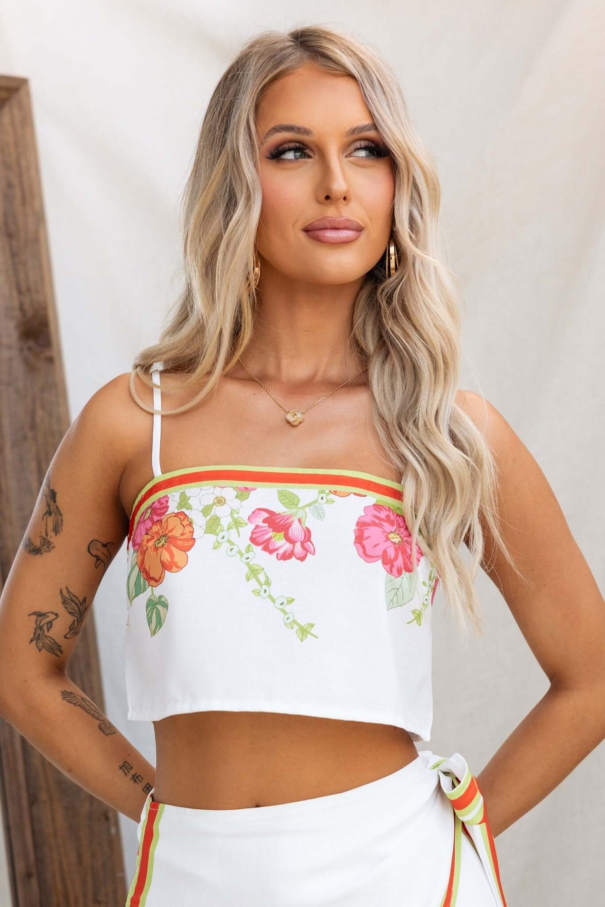 Model wearing Julissa Top, a white floral crop top with adjustable straps, showcasing a summer style.