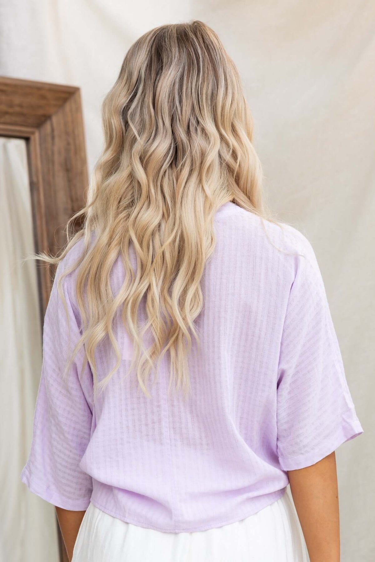 Back view of a woman wearing a lavender batwing sleeve Floe Top with relaxed fit.