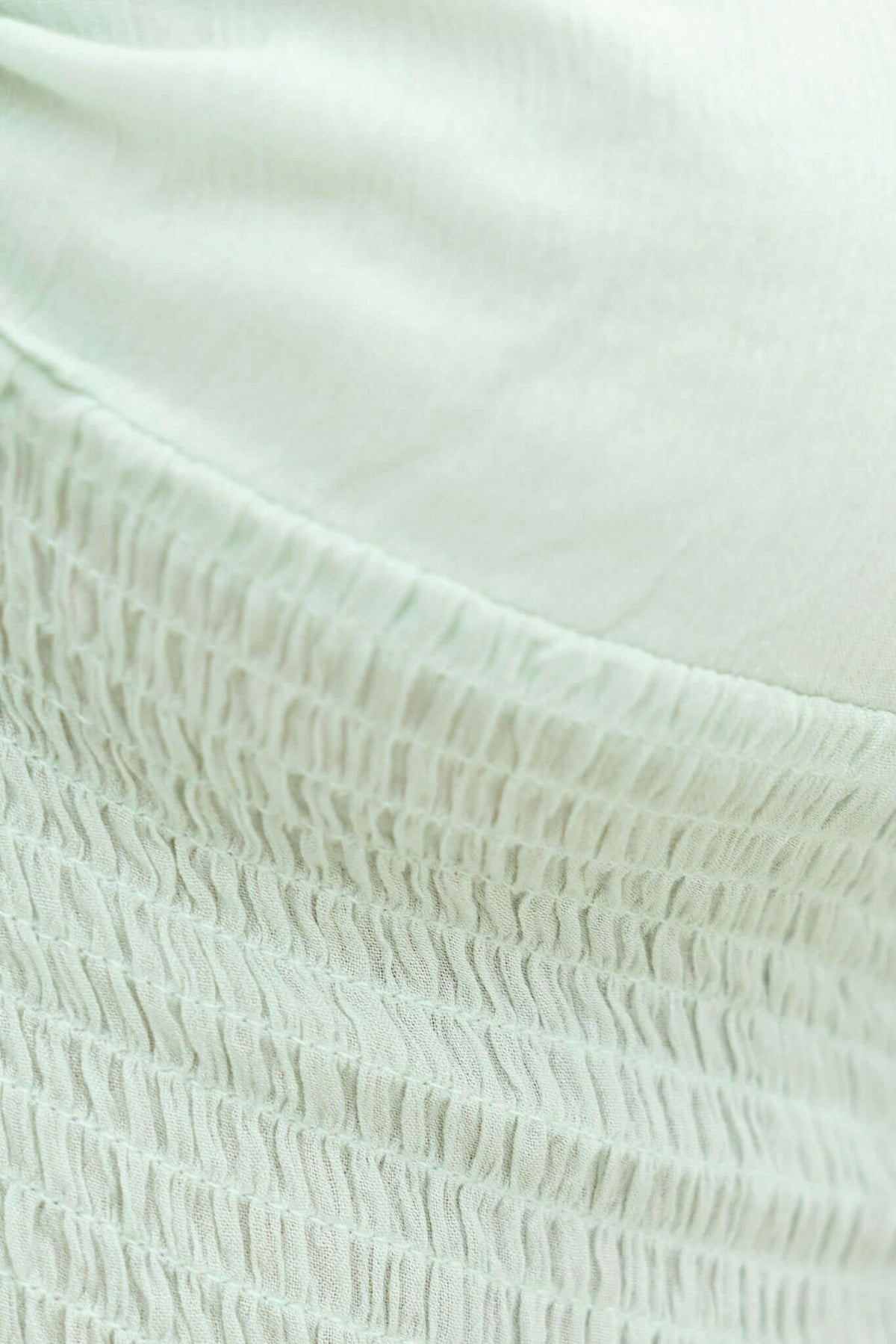 Close-up of the Alynn Top showing elastic and lined details in a soft mint green fabric.