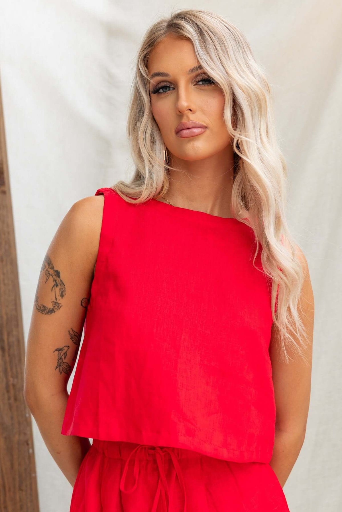 Model wearing the Orson Top in bright red linen with a relaxed fit and button detail at the back.