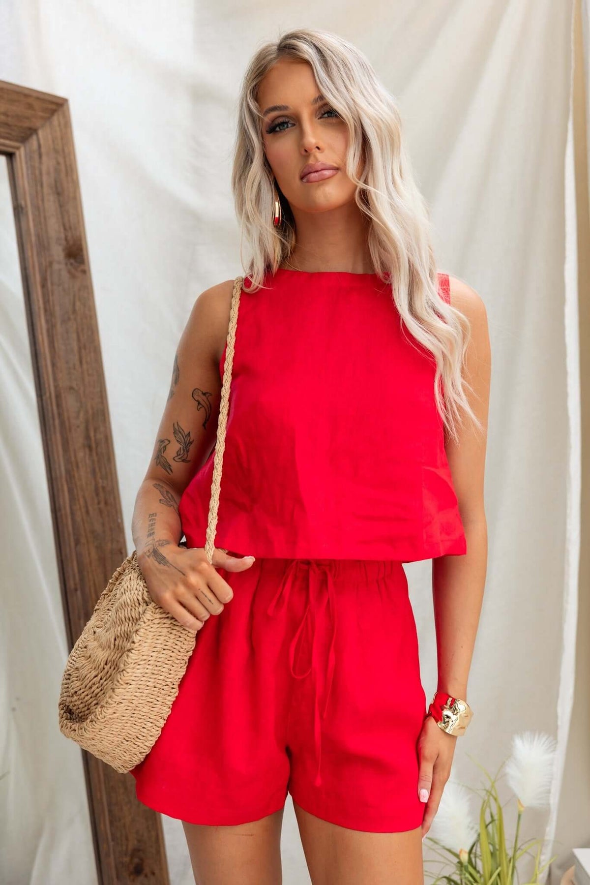 Model wearing bright red Orson Shorts set with elastic waistband and stylish woven bag.