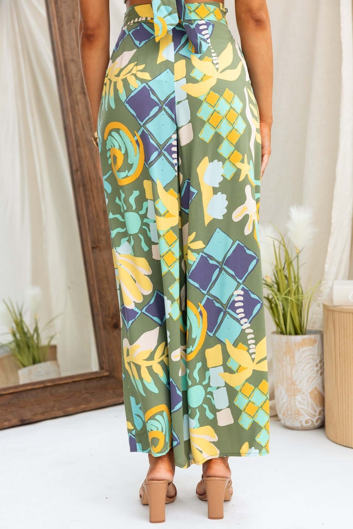 Back view of Warana Pants featuring vibrant patterns, mid-high waist, removable tie, and pockets.