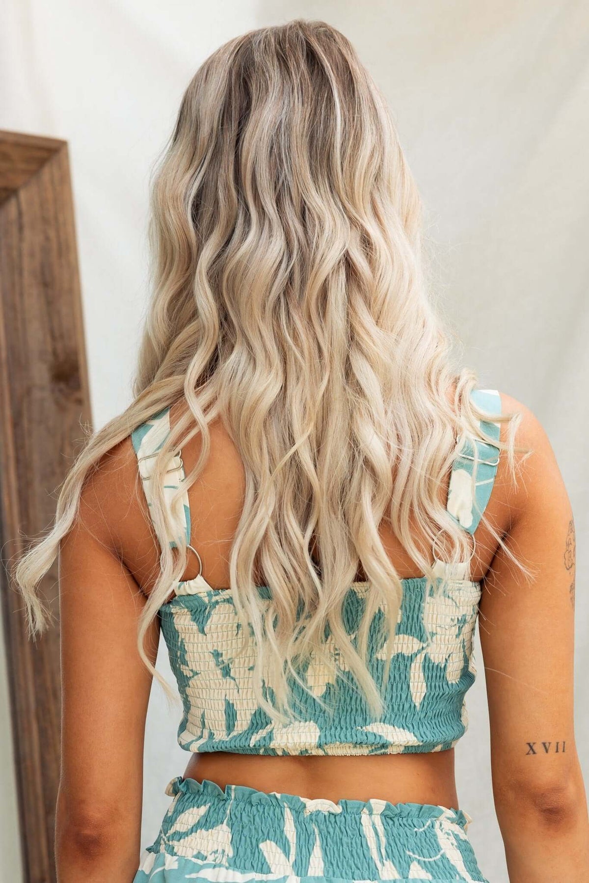 Back view of a woman in a floral adjustable strap top, showcasing wavy hair and a casual summer style.