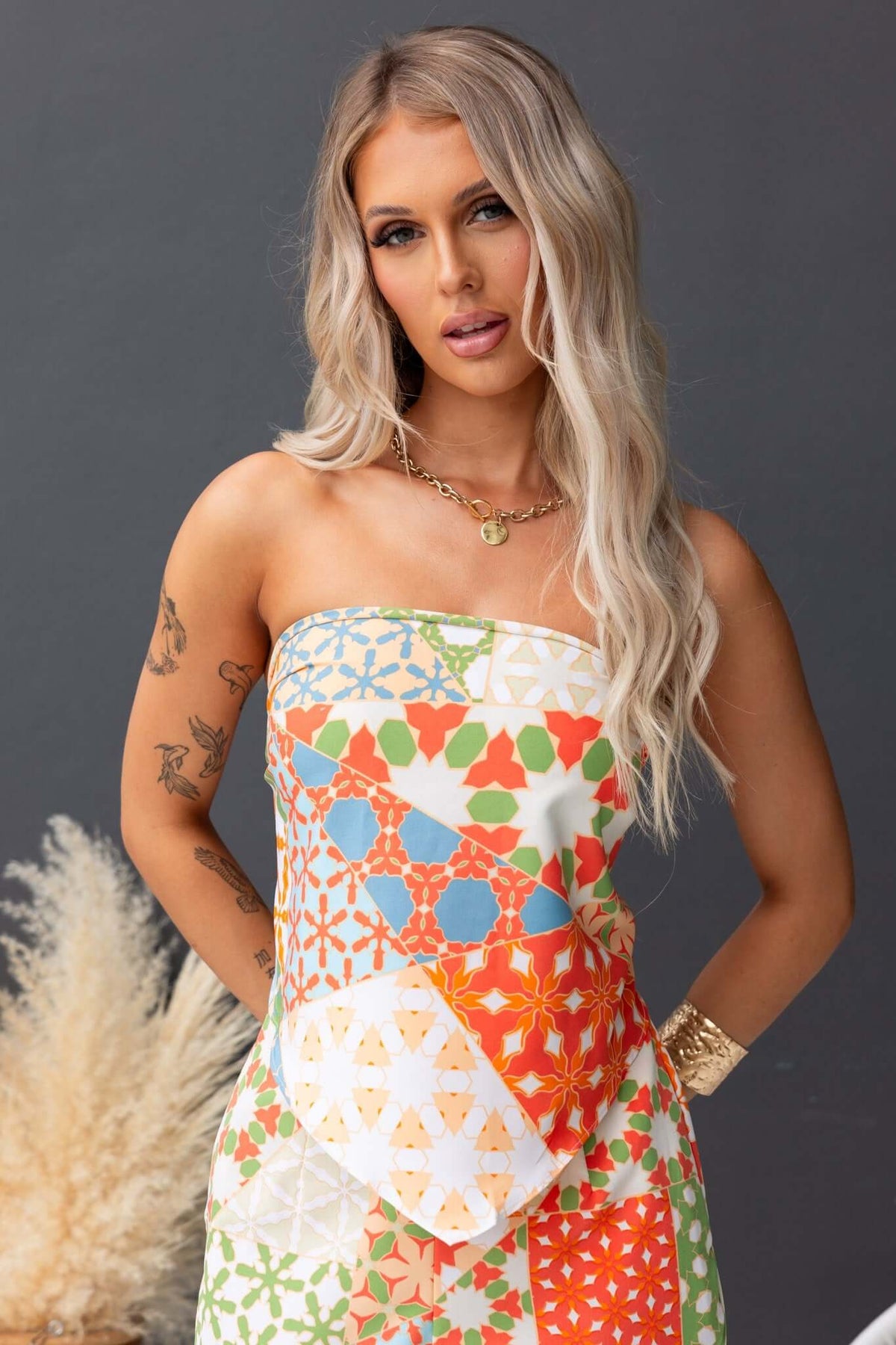 Lorinda Top featuring colorful patchwork design, worn as a versatile scarf top by model with long blonde hair.