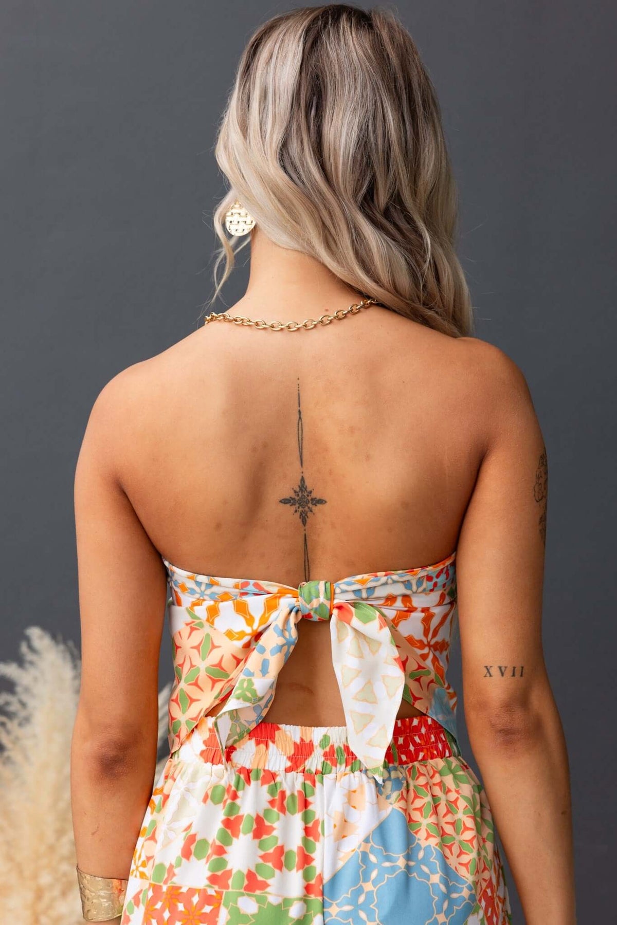 Back view of Lorinda Top showing scarf design, tie detail, and colorful floral pattern worn by model.