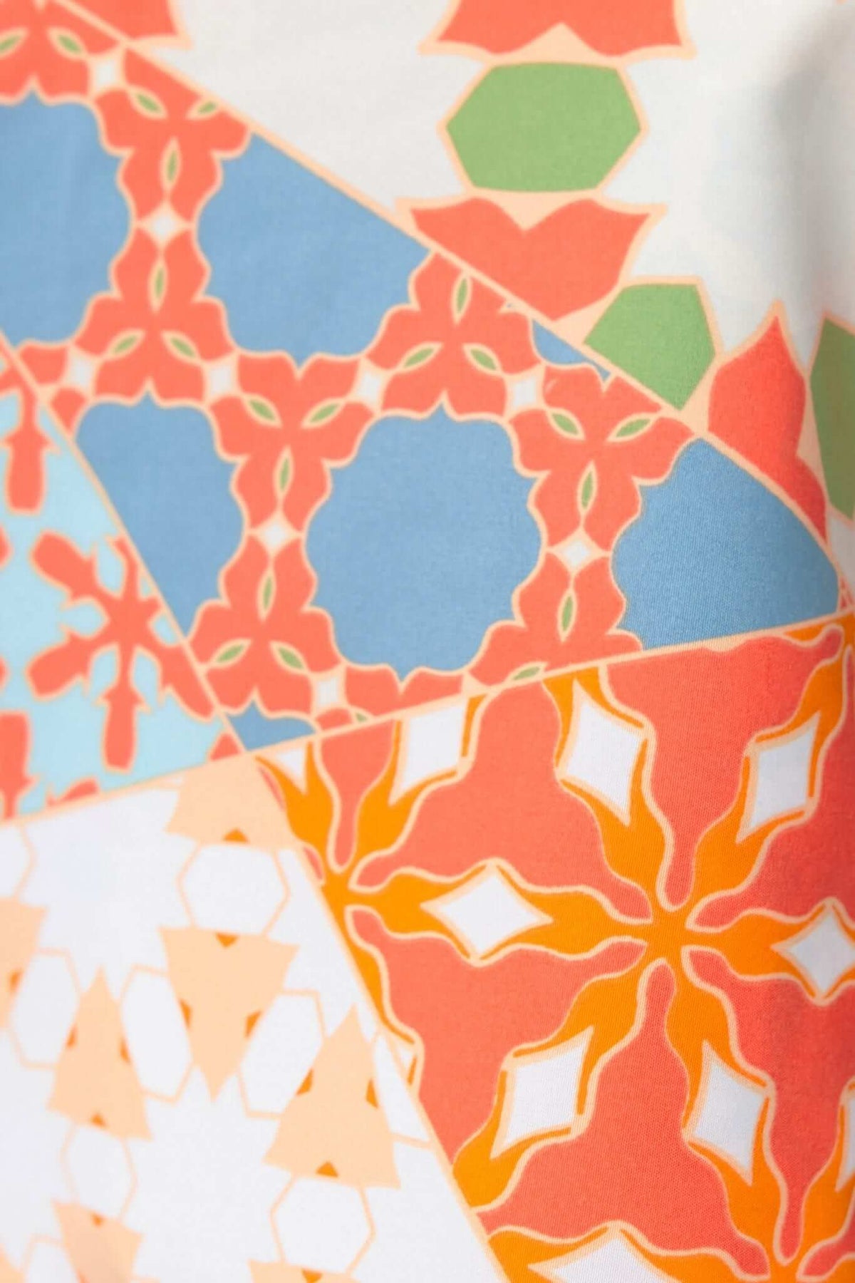 Colorful geometric pattern featuring shades of blue, orange, green, and coral on fabric.