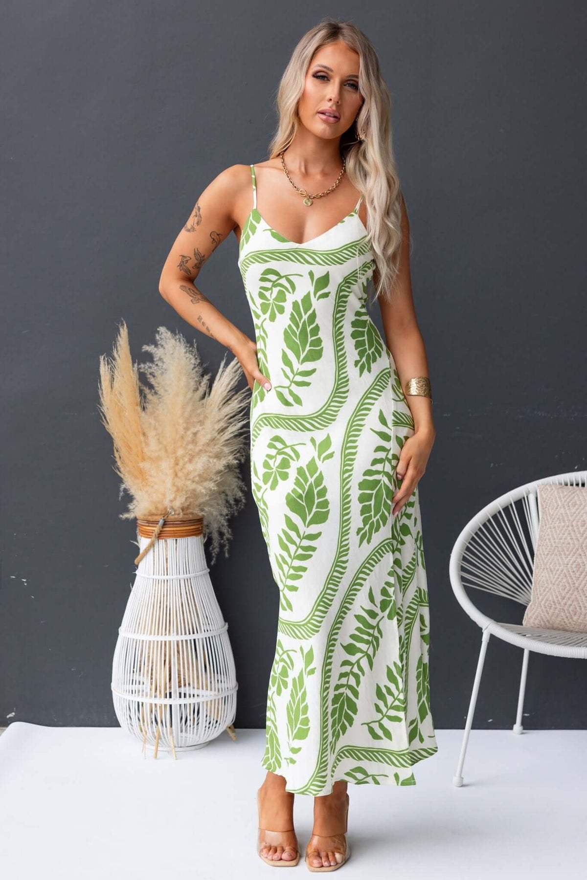 Model wearing the Kalinda Maxi Dress featuring a green leaf print, adjustable straps, and a V-neckline.