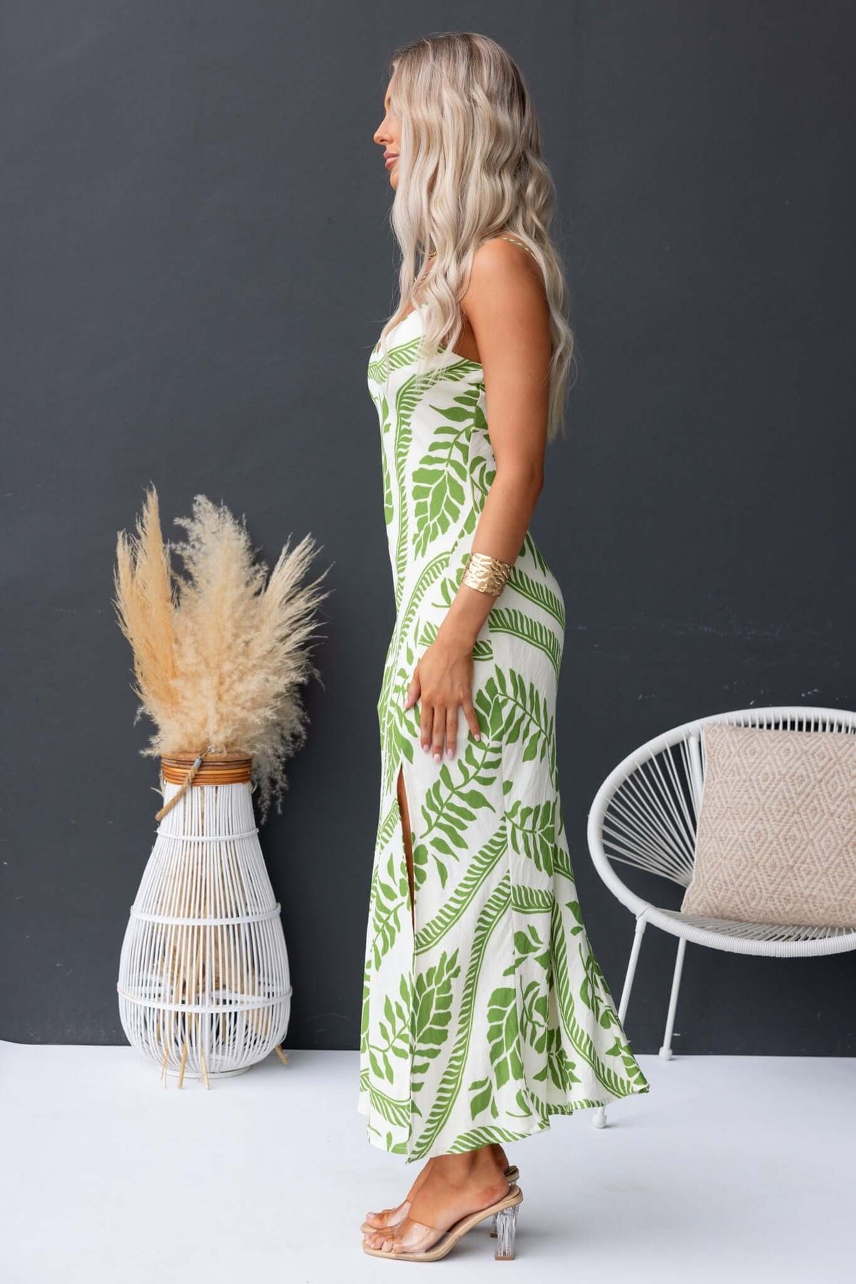 Model showcasing the Kalinda Maxi Dress with adjustable straps and front split, featuring a green and white leaf pattern.