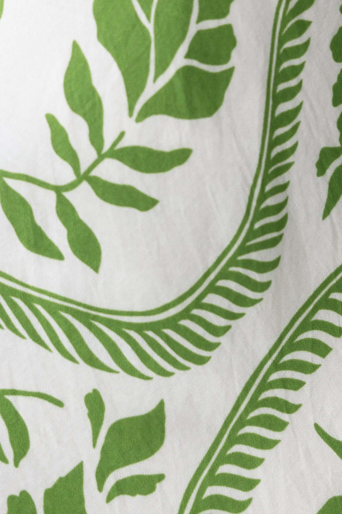 Close-up of green leaf pattern on white fabric, ideal for fashion and textile design.