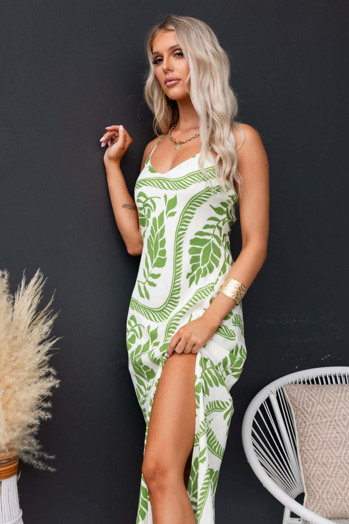 Model in a Kalinda Maxi Dress featuring green botanical prints, adjustable straps, and a front split.