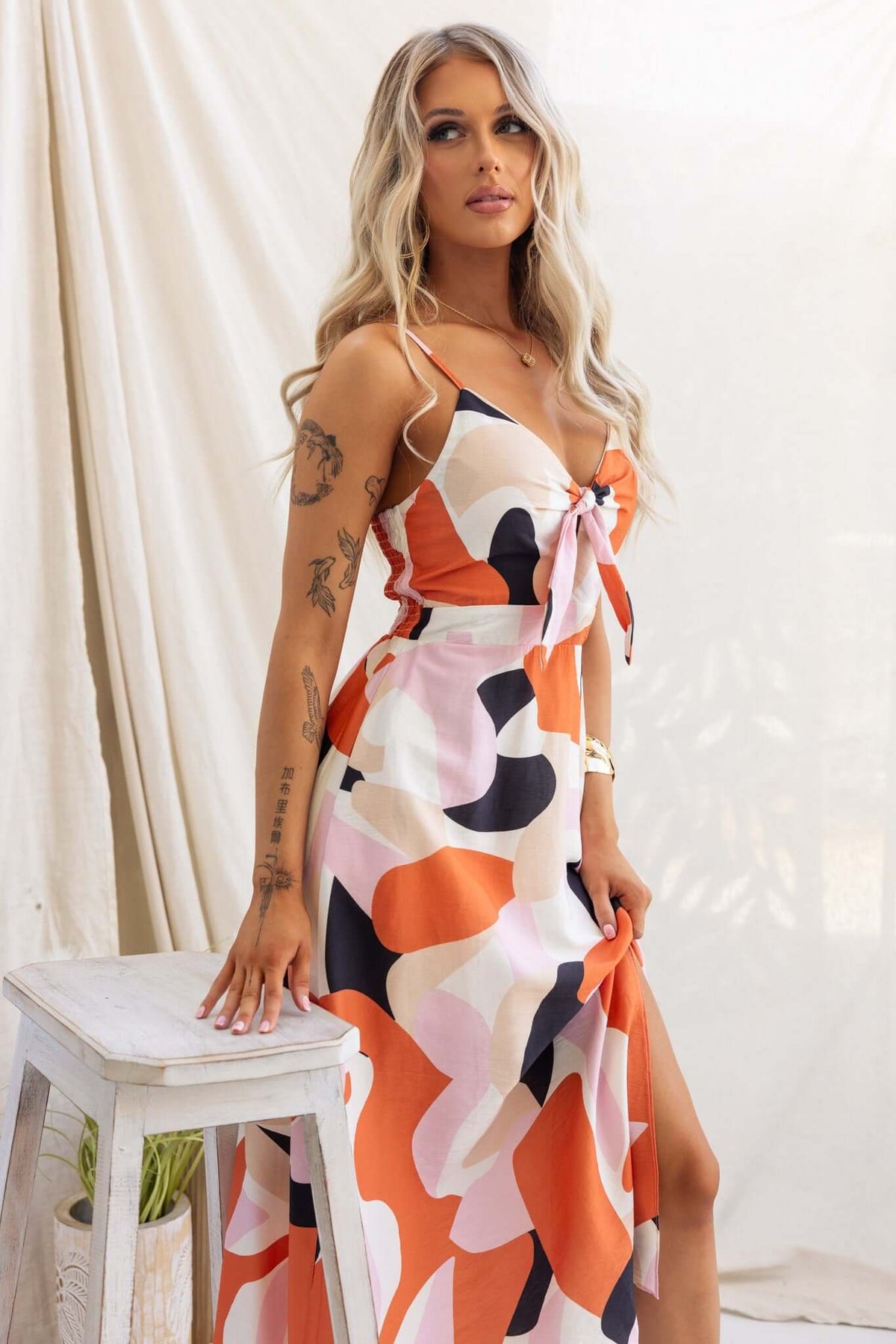 Modina Midi Dress with adjustable straps, colorful abstract pattern, tie at bust, and front split showcasing stylish summer fashion.