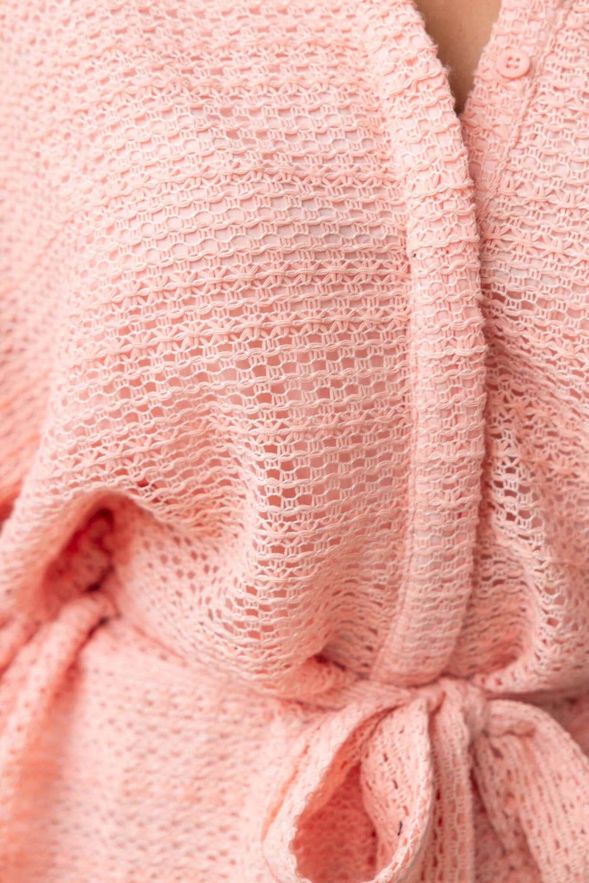 Close-up of the Joner Playsuit in soft pink with textured fabric and a tie waist detail.