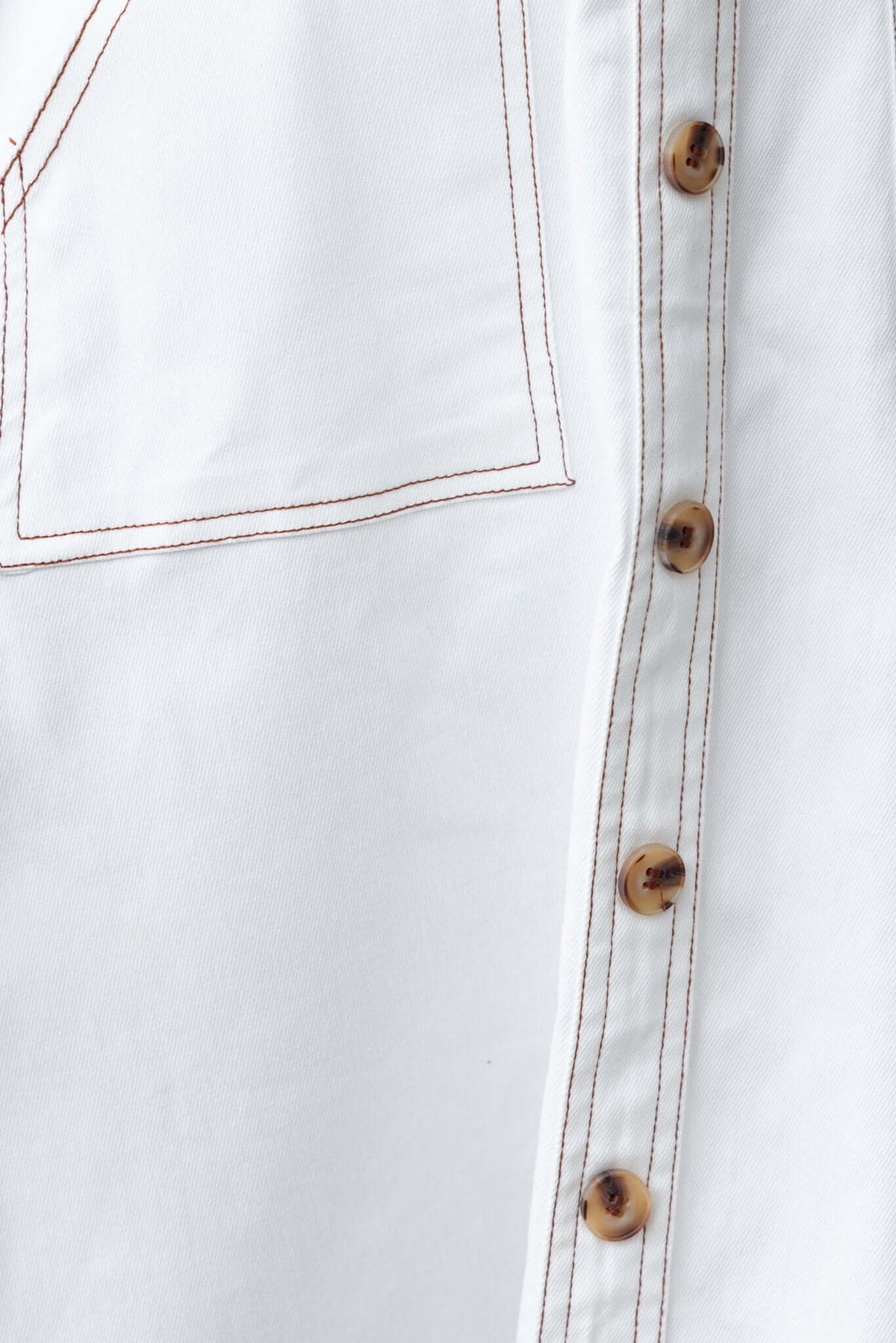Close-up of Karta Denim Midi Dress fabric featuring faux button detail and pocket.