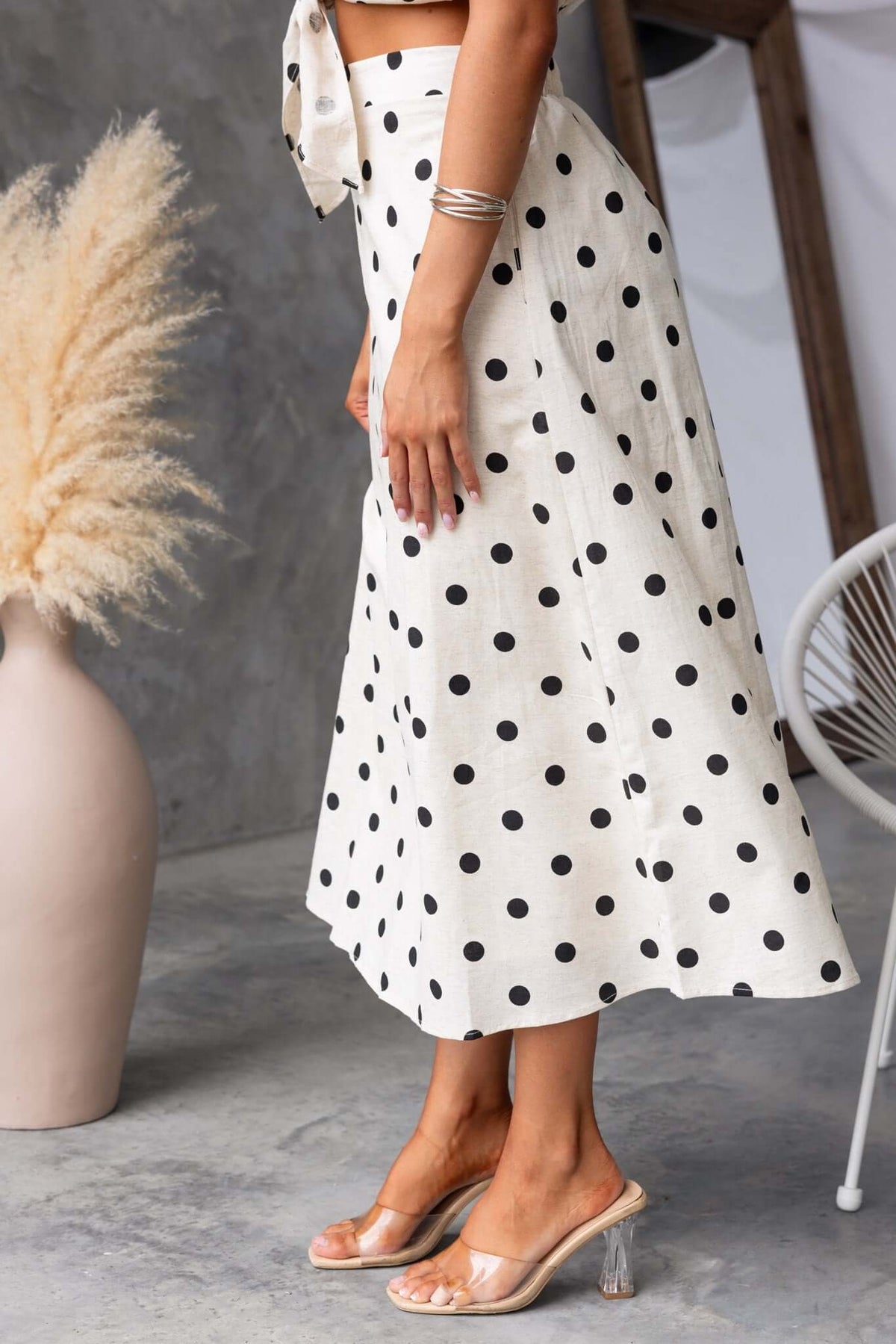 Carrion midi skirt in cream with black polka dots, featuring elastic waistband and pockets, styled with heeled sandals.