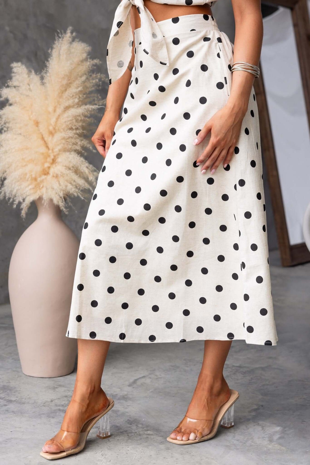 Carrion midi skirt with polka dots, featuring a mid-high waist, elastic waistband, and side pockets, modeled with clear heels.