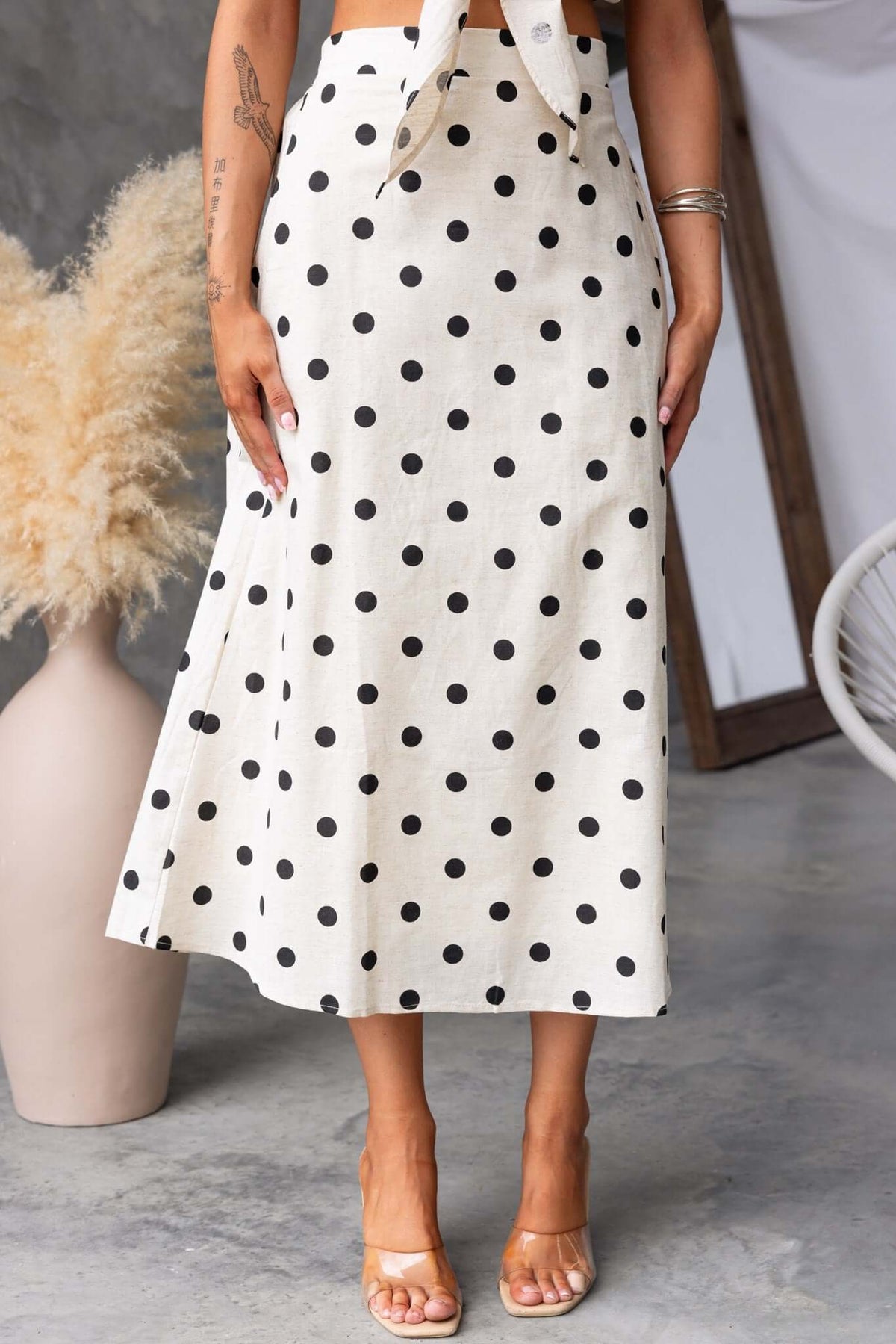 Carrion Midi Skirt with polka dots, mid-high waist, elastic waistband, and pockets, styled with a cropped top.