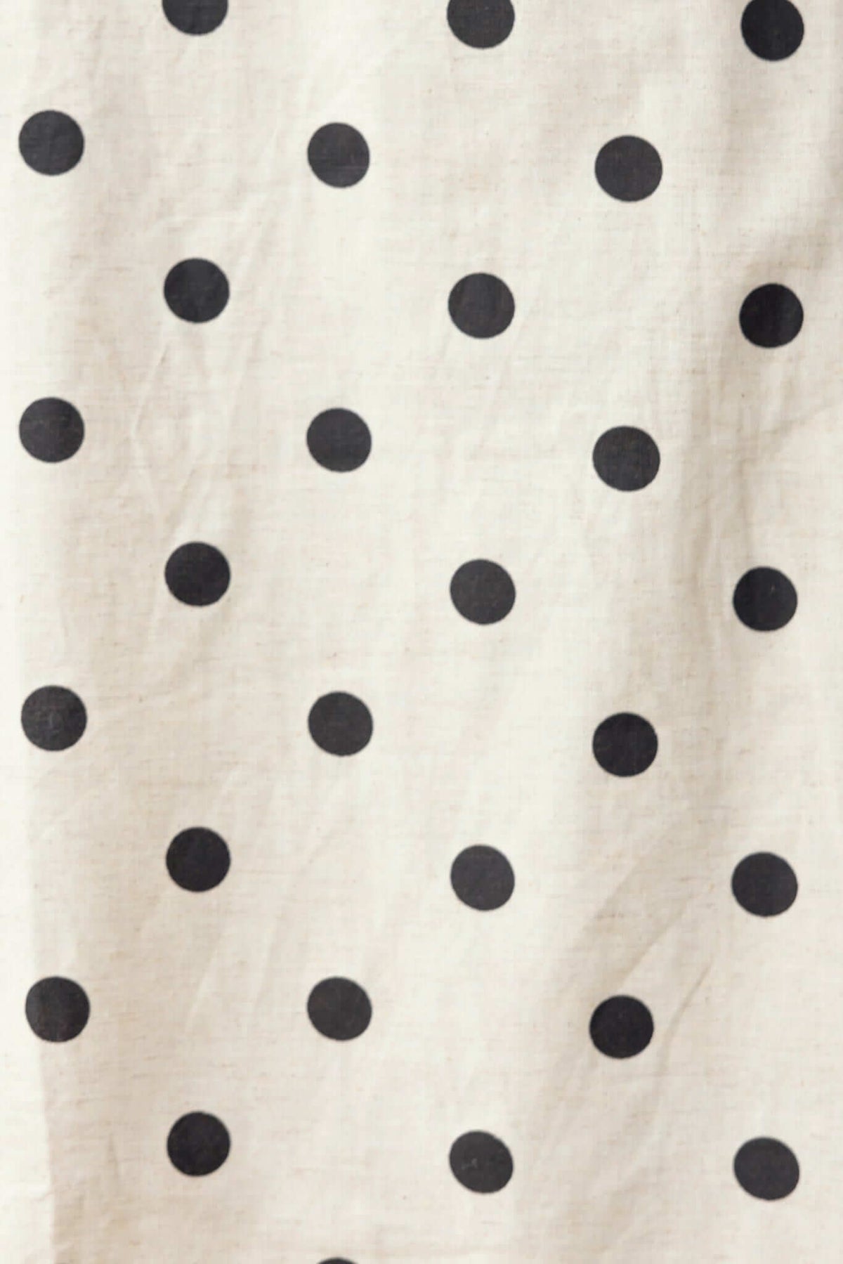 Close-up of fabric with black polka dots on a beige background, ideal for the Carrion Midi Skirt.