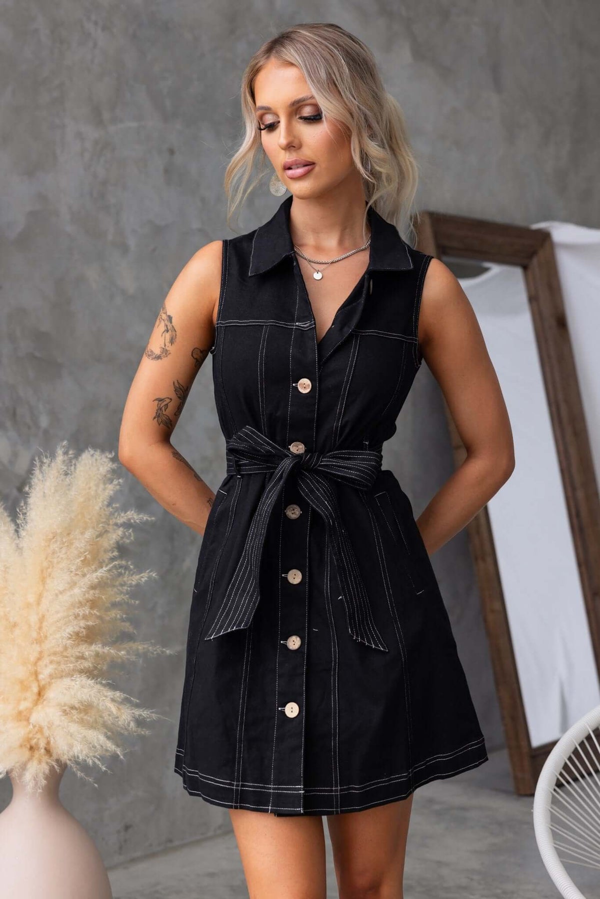 Women’s sleeveless denim dress with collar, button-up front, pockets, and removable tie belt.