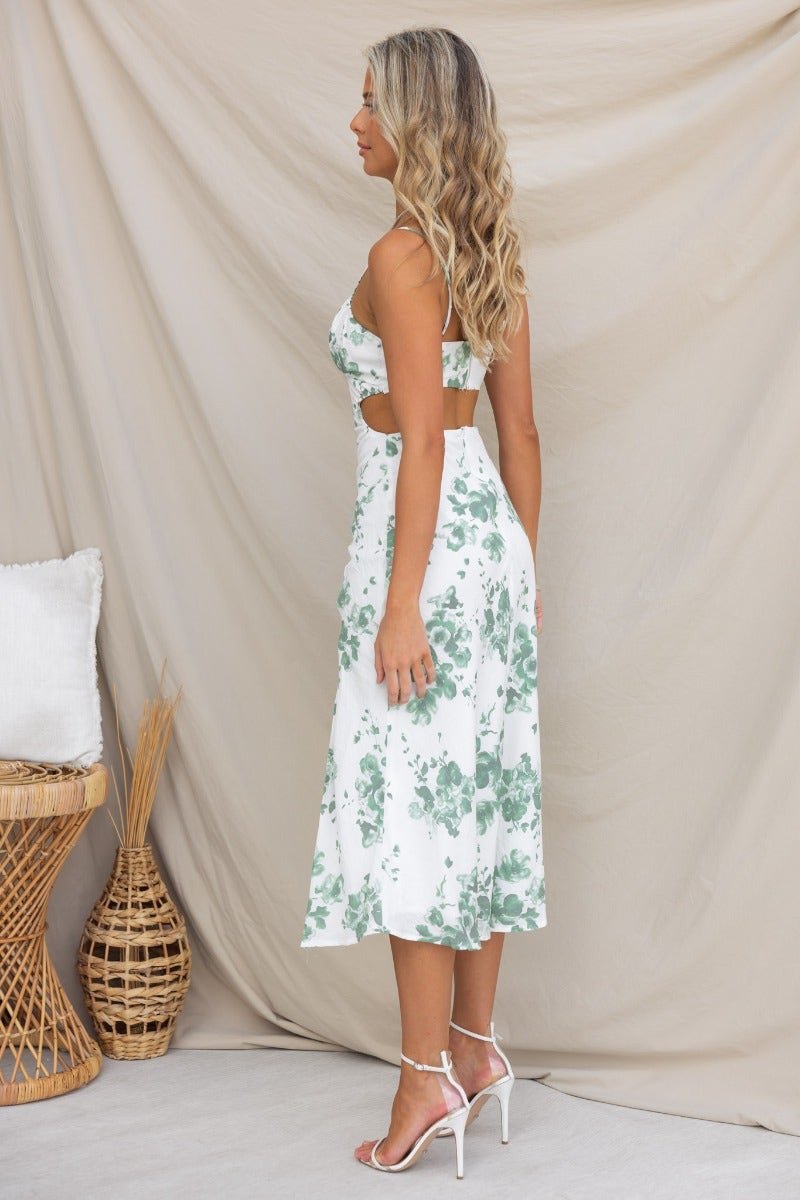 Side view of a woman in a floral print midi dress with adjustable straps and a split front.