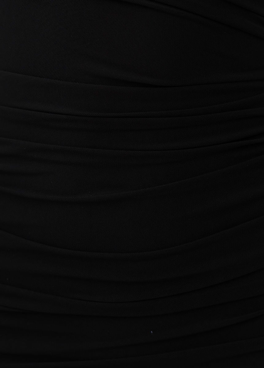 Close-up of black mesh overlay dress with ruching detail on the sides, highlighting the stretchy fabric.
