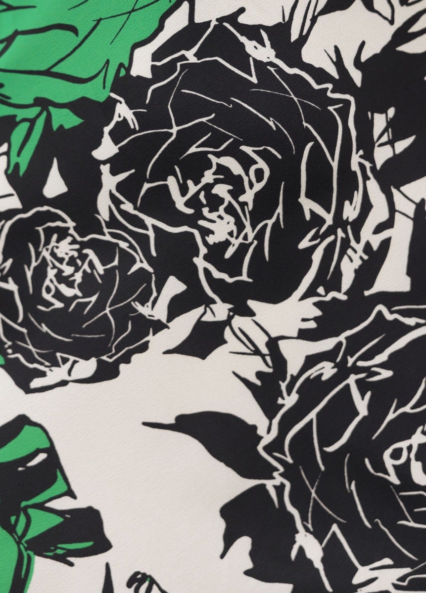 Close-up of black and green floral print fabric featuring roses on a cream background.