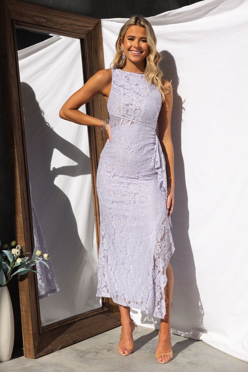 Model wearing a lavender lace maxi dress with ruffle trim, high split, and high neckline, showcasing elegant summer style.