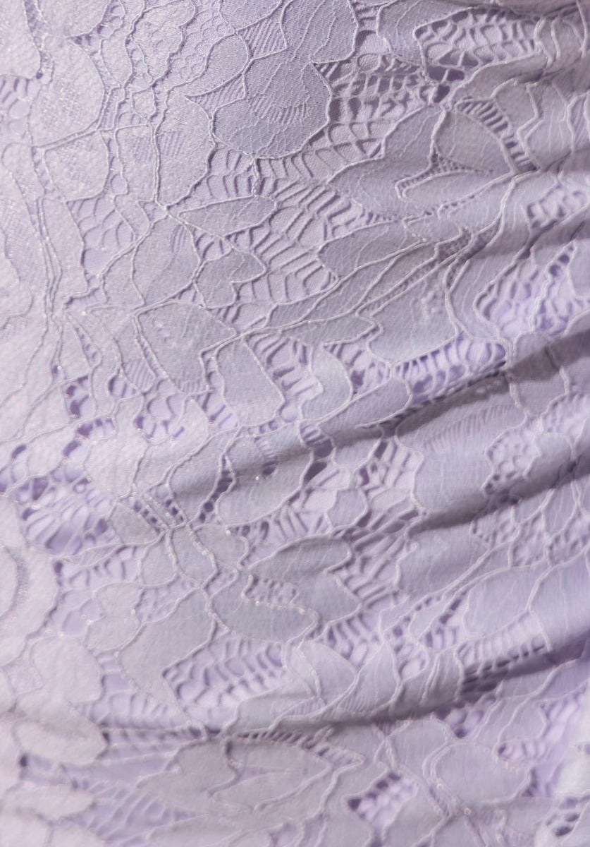Close-up of delicate lace fabric in pastel purple, showcasing intricate patterns and texture for a maxi dress.