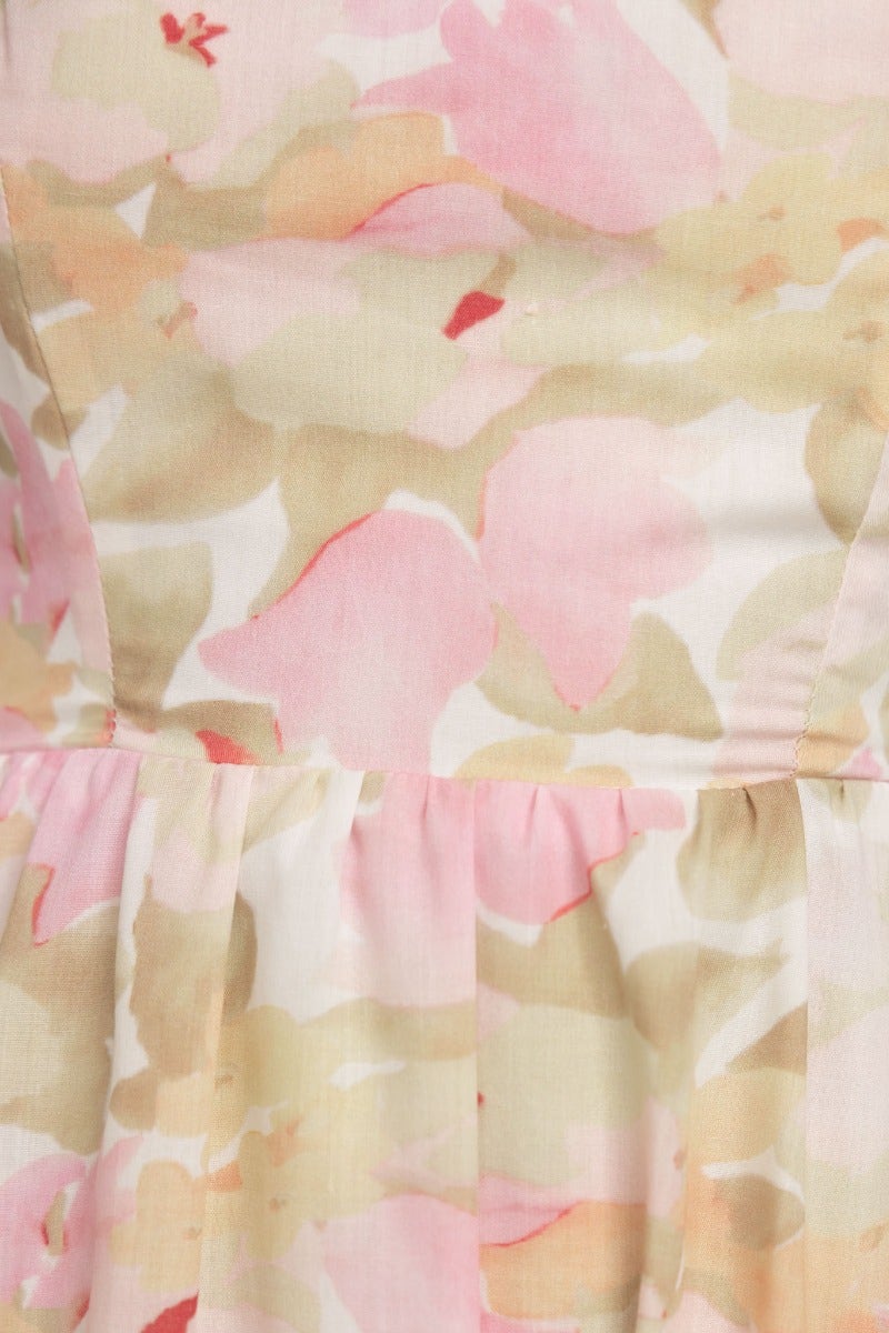 Close-up of floral print fabric in soft pink and beige tones, featuring delicate textures and a flowing design.
