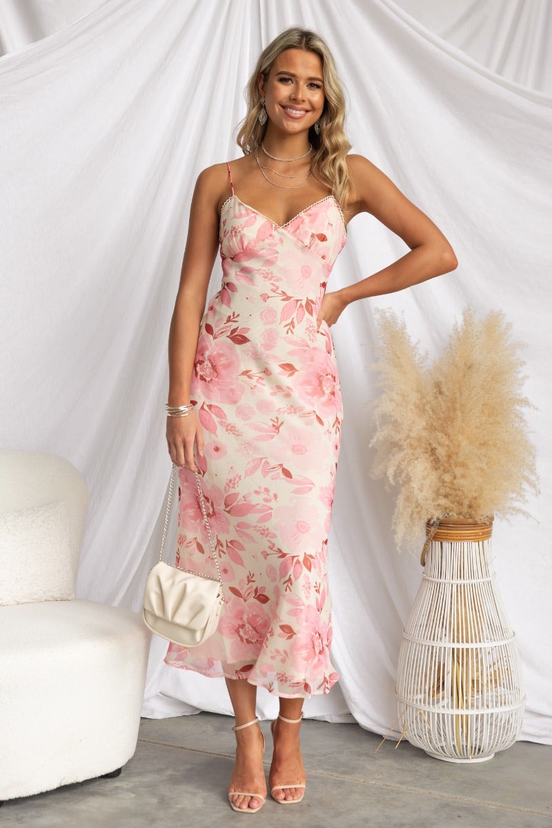 Jasia Midi Dress featuring floral print, adjustable thin straps, and a flowy silhouette, styled with a chic bag.