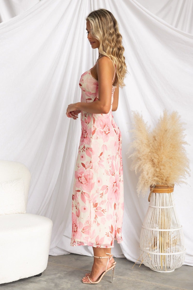 Side view of a floral print Jasia midi dress with adjustable straps on a model, styled with a neutral backdrop.