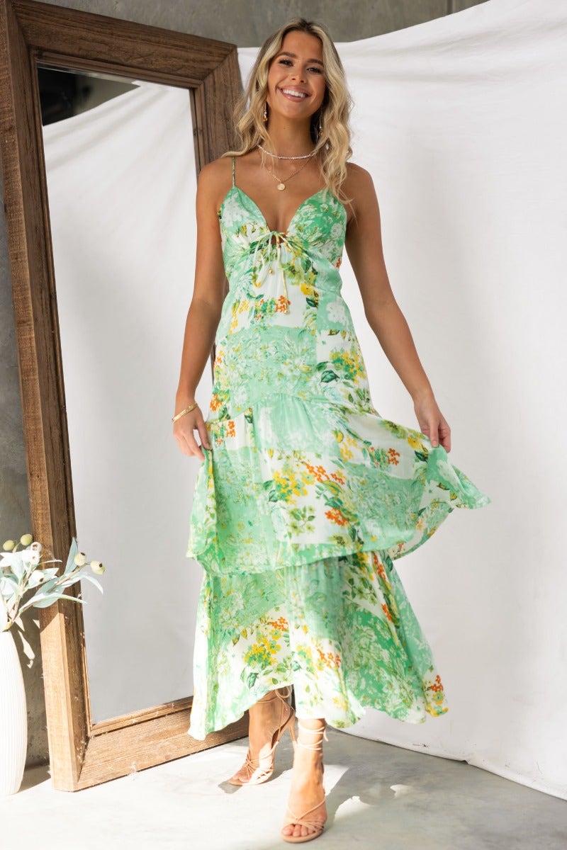 Model wearing a floral print Wildest Dreams Maxi Dress with adjustable straps and tie detail, posed in a stylish setting.