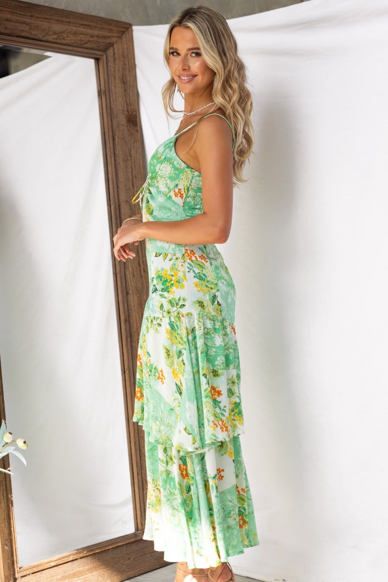 Model wearing the Wildest Dreams Maxi Dress in a floral print, showcasing adjustable straps and tiered design.