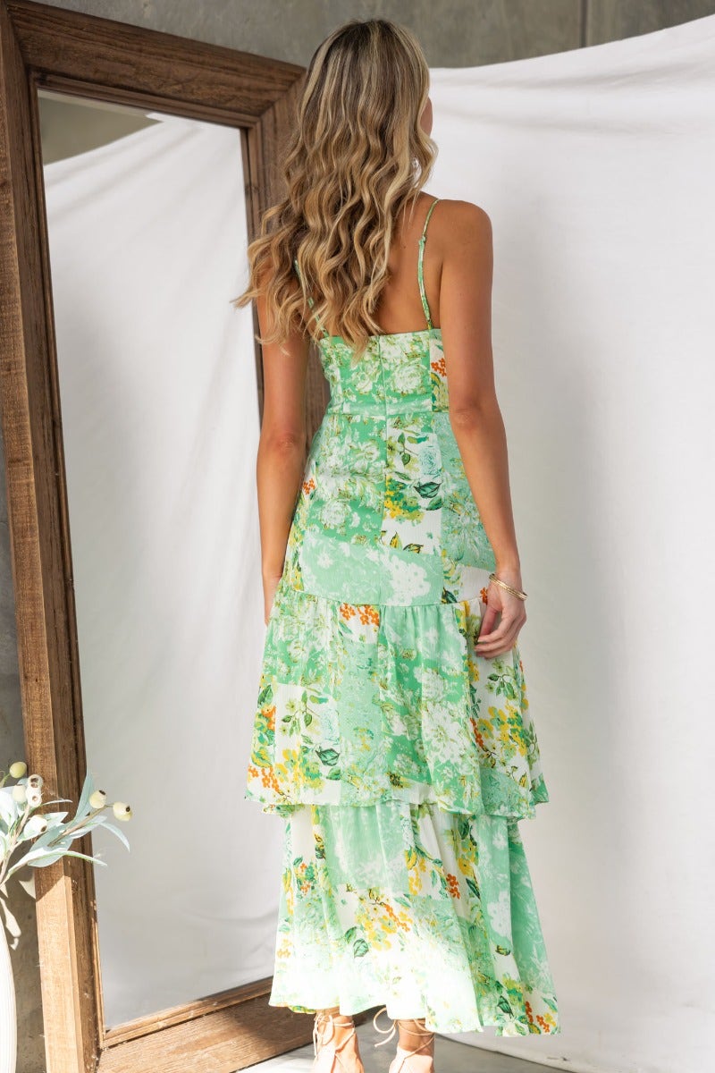 Back view of a model in a floral print Wildest Dreams maxi dress with adjustable straps and tiered design.