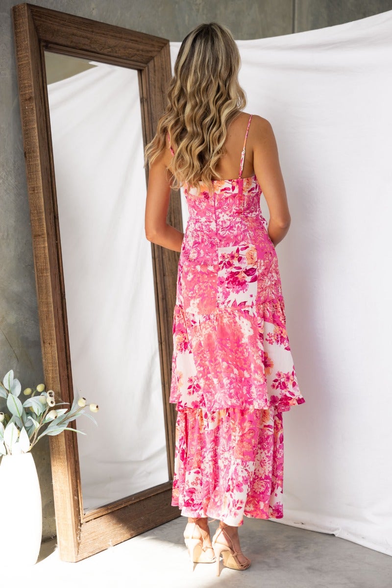 Model showcasing the back of a floral print pink maxi dress with adjustable straps and layered design.