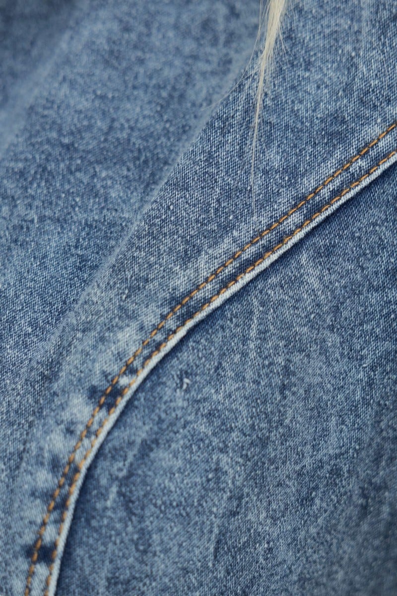 Close-up of the denim fabric showing texture and stitching details of the On Track Denim Playsuit.