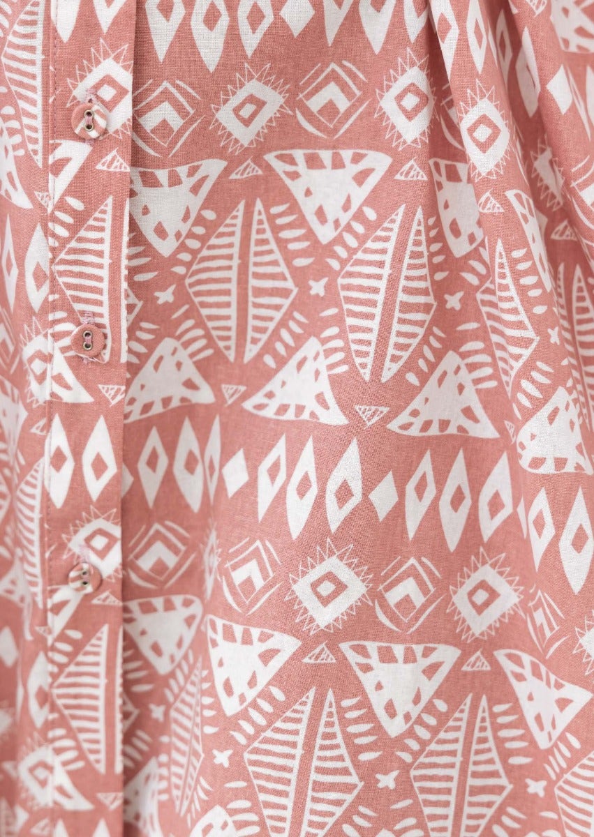 Close-up of Dillon Dress showing pink cotton blend fabric with white geometric patterns and button details.