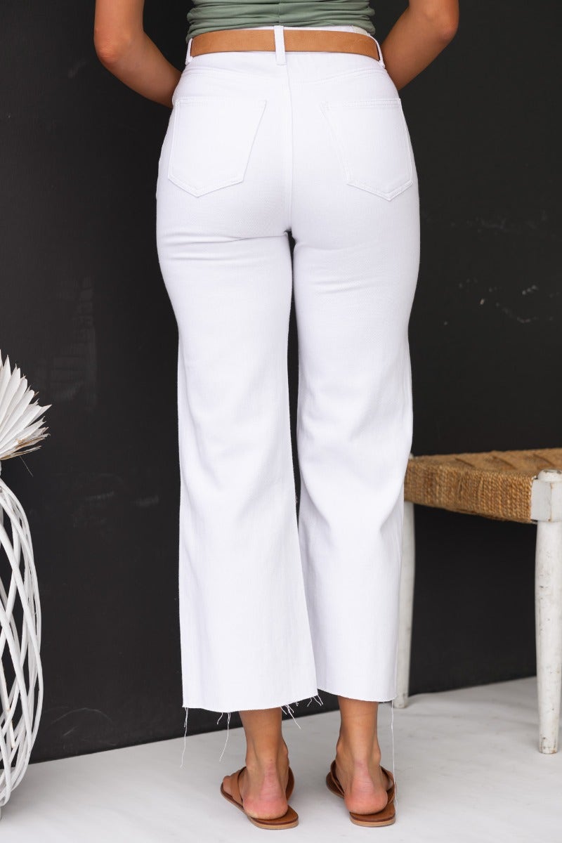 Back view of Avril Jeans, featuring wide legs, mid-high waist, and raw cut hem, styled with a green top.