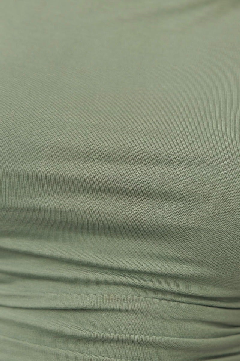 Close-up of the ruched detail on a green cotton blend top, showcasing its soft stretch fabric and elegant design.