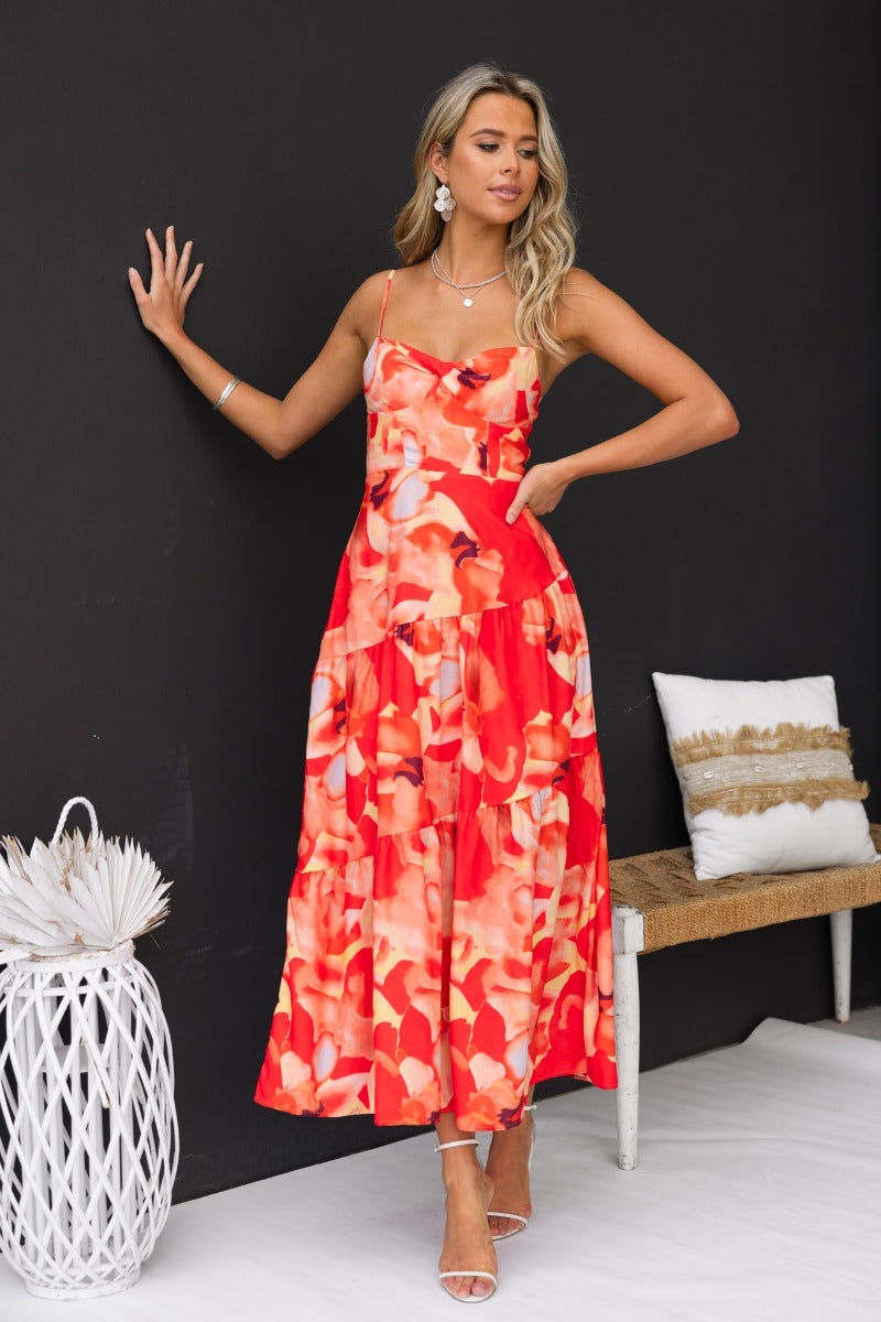 Model wearing a floral print red Scorpio Maxi Dress with adjustable straps and twist detail.