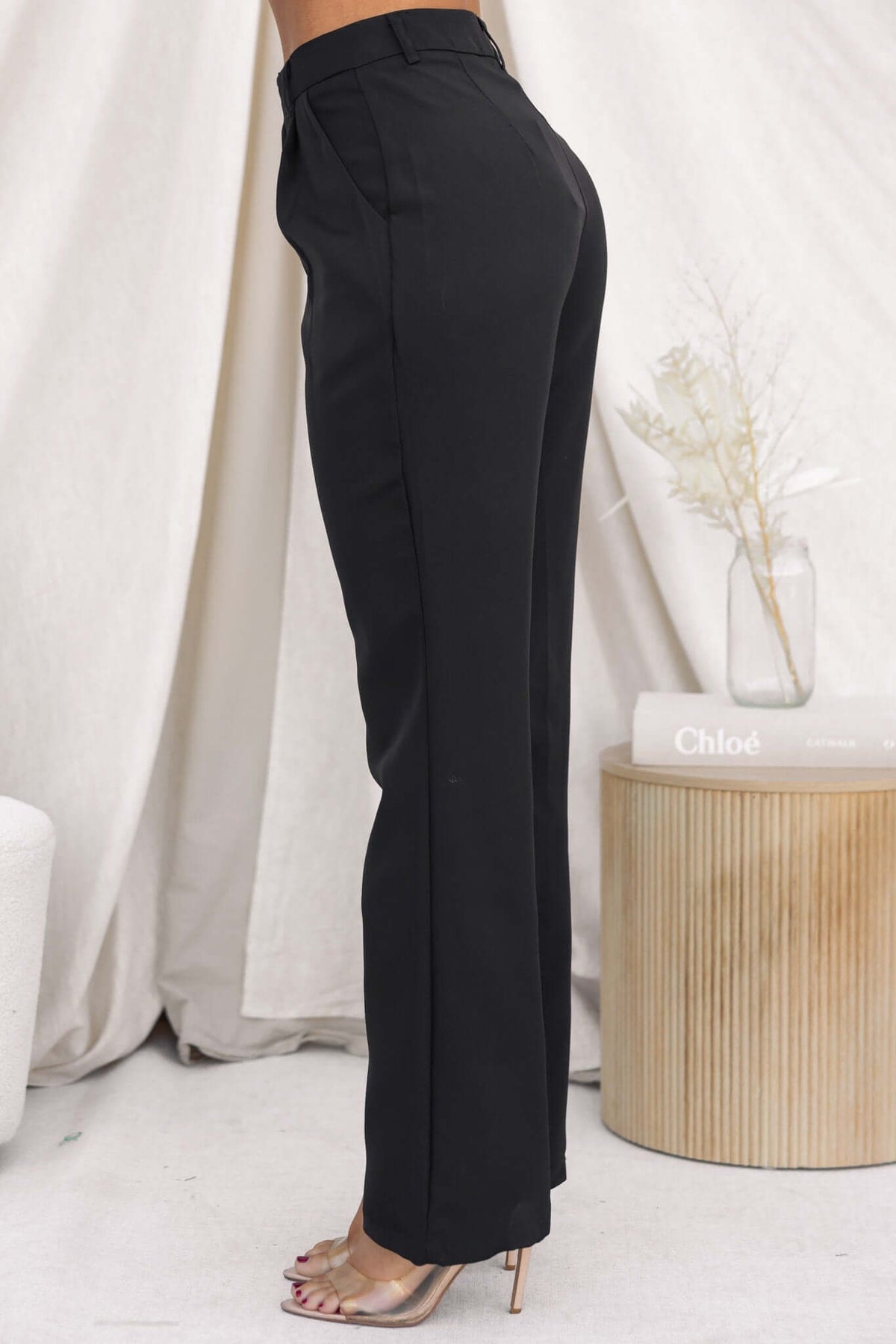 Ulani Pants: Mid-high waist black pants with pockets, non-lined and non-stretch design, model shown in size 6/XS.