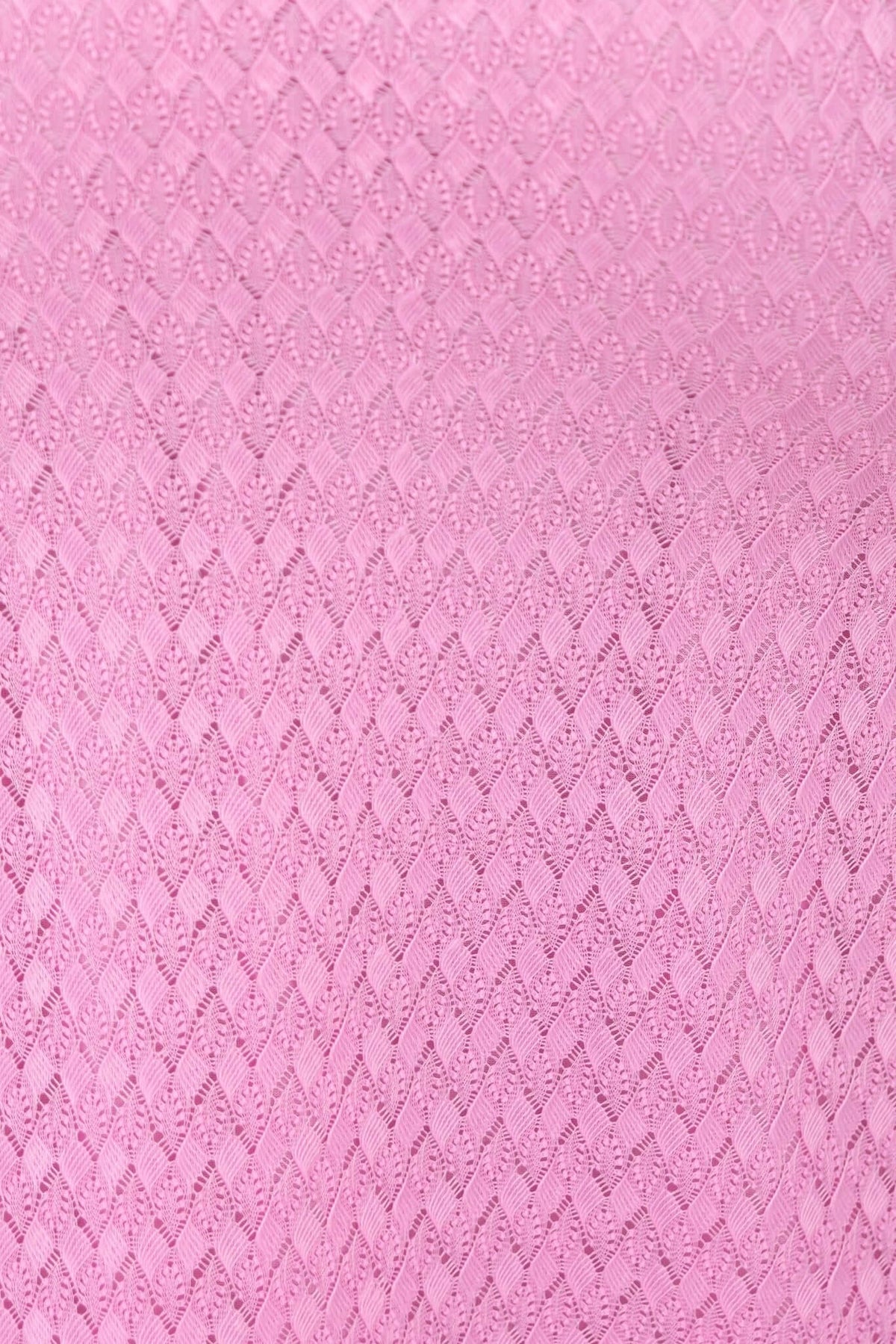 Close-up of textured pink fabric with a diamond pattern, ideal for a stylish dress.