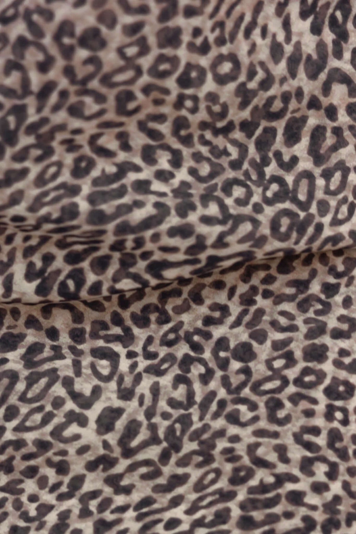 Close-up of leopard print fabric, showcasing a soft texture and wild pattern ideal for fashion designs.