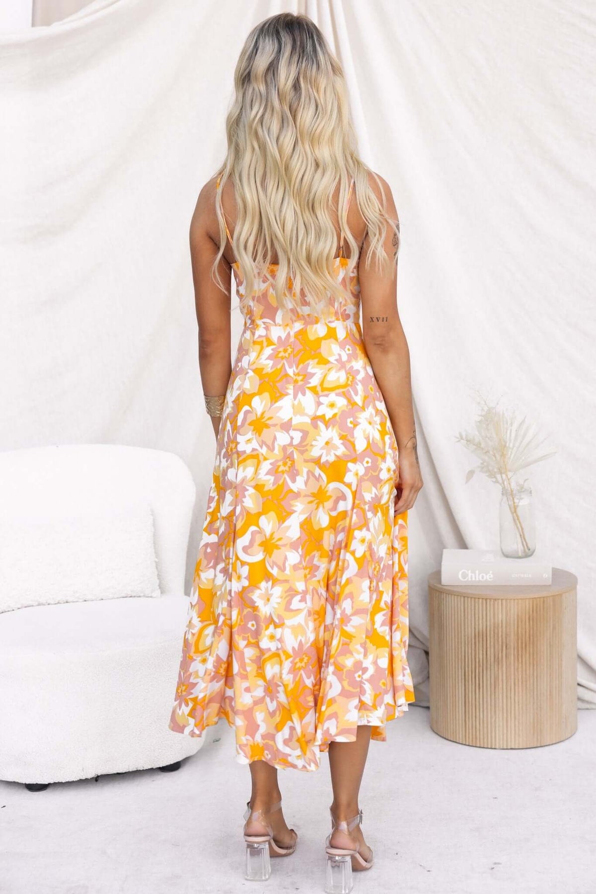 Back view of Sandra Midi Dress with floral pattern in orange and yellow, showcasing adjustable straps and flowing hem.