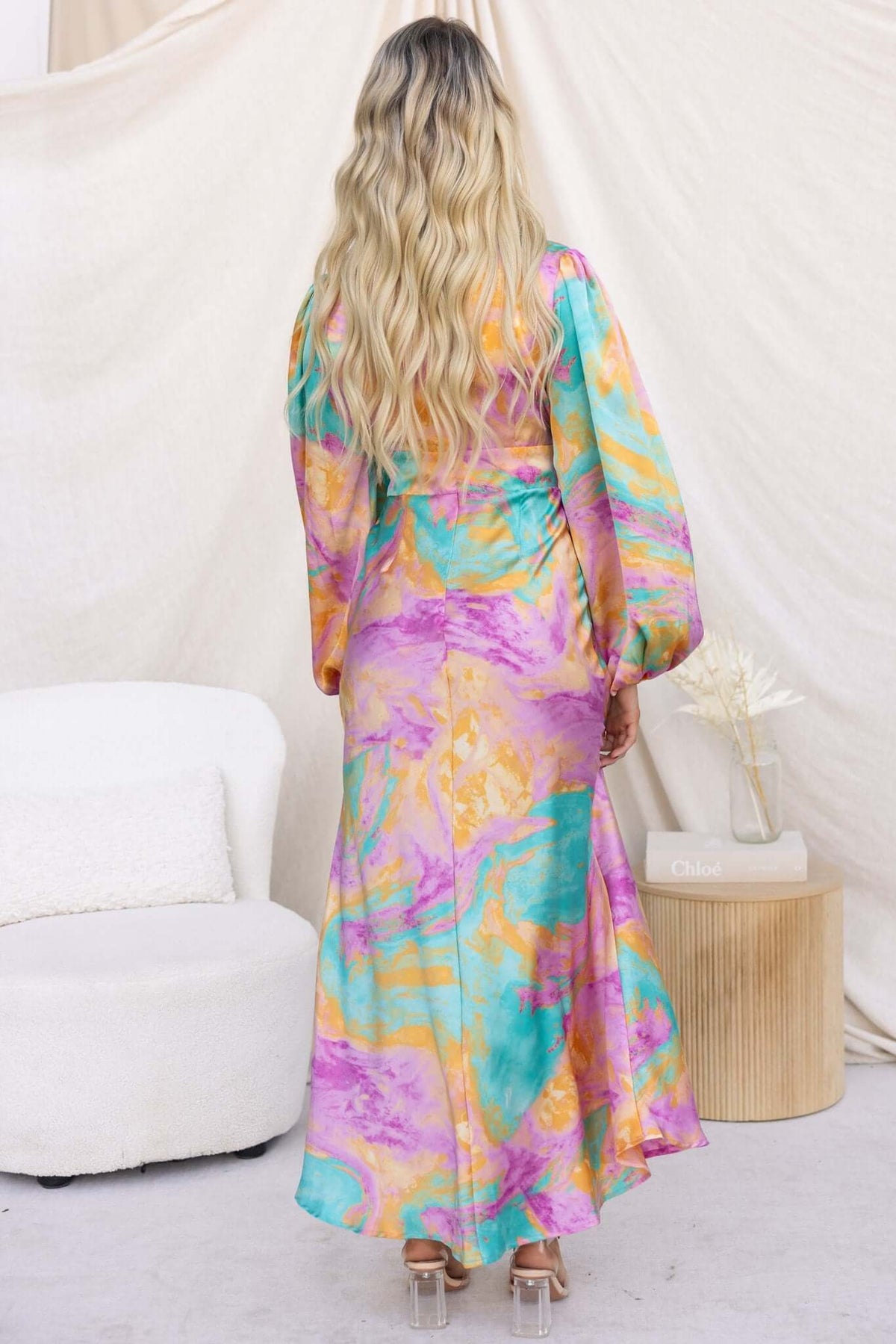 Woman wearing a colorful With You Maxi Dress with a V-neckline and cut-out at the waist, seen from the back.