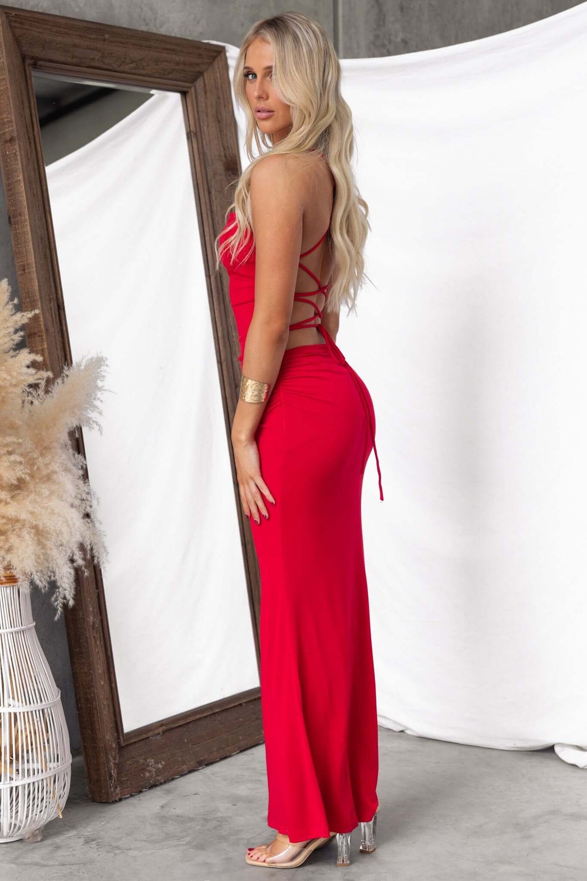 Model showcasing the Perris Maxi Dress in red, featuring adjustable tie straps and a sleek, fitted design.