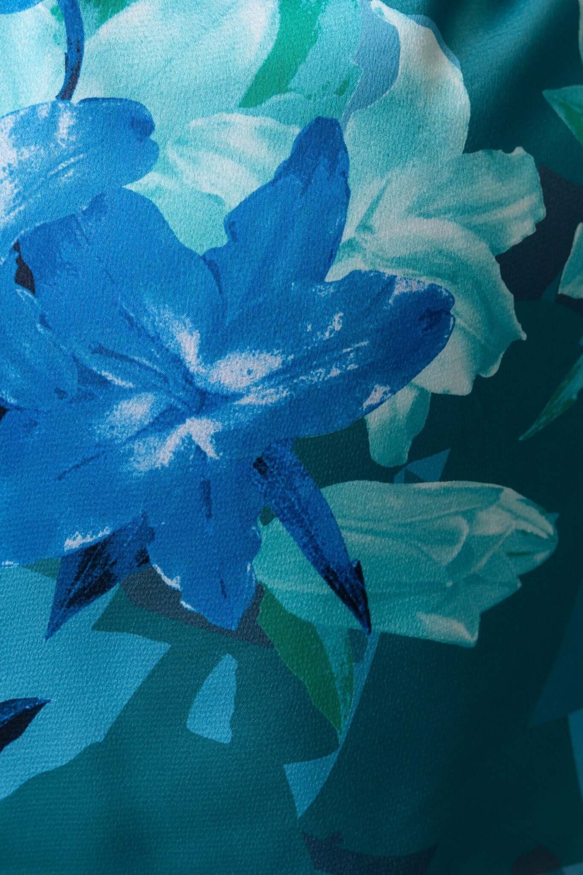 Close-up of vibrant blue floral print on fabric, showcasing detailed blossoms in shades of blue and green.